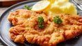 Delicious authentic breaded and deep-fried Wiener schnitzel served with lemon and mashed potatoes on a a plate