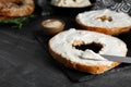 Delicious bagel with tofu cream cheese and knife on black table, closeup. Space for text