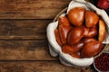 Delicious baked pirozhki in wicker basket, apple and cranberry on wooden table, flat lay. Space for text Royalty Free Stock Photo