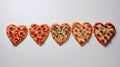 Delicious baked pizzas in the shape of a heart, with various vegetables and sausage, on a white background