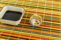 Delicious baked tempura roll with salmon stands next to soy sauce stands on a bamboo mat Royalty Free Stock Photo