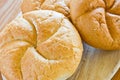 Delicious baking round buns made on a wooden table background.