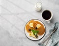 Delicious banana pancakes with fresh fruit slices, berries, mint and honey on a light background with a cup of black coffee, soy Royalty Free Stock Photo