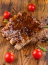 Delicious barbecued ribs seasoned with a spicy basting sauce and served with chopped fresh vegetables on an old rustic Royalty Free Stock Photo