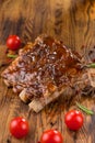 Delicious barbecued ribs seasoned with a spicy basting sauce and served with chopped fresh vegetables on an old rustic Royalty Free Stock Photo