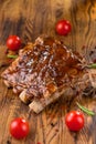 Delicious barbecued ribs seasoned with a spicy basting sauce and served with chopped fresh vegetables on an old rustic Royalty Free Stock Photo