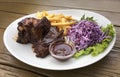 Delicious barbecued ribs seasoned with a spicy basting sauce and served with chopped fresh vegetables on an old rustic wooden chop Royalty Free Stock Photo