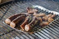 Delicious barbecued sausages sizzling over a campfire. Royalty Free Stock Photo