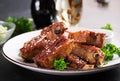 Delicious barbecued spare ribs on plate on dark background.