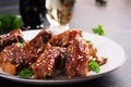 Delicious barbecued spare ribs on plate on dark background.
