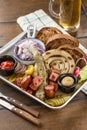 Delicious bbq Fried sausages with cabbage, pickles and potato on platter and glass of beer on wooden table Royalty Free Stock Photo