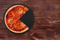 Delicious BBQ pizza with ham, bbq sauce, bacon and salami, without a quarter on a black slate platter which is on wooden table Royalty Free Stock Photo