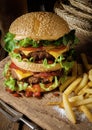 Delicious beef burger with chips and beer on wooden table. Royalty Free Stock Photo