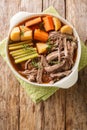 Delicious beef pot roast with potatoes, celery and carrots with thyme and rosemary closeup in the bowl. Vertical top view Royalty Free Stock Photo