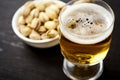 Delicious beer in a glass and pistachios in a white bowl on an old black table