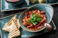 Delicious beetroot soup in bowl, solyanka with meats served with croutons over a dark background, close up view. Concept of