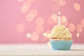 Delicious birthday cupcake with burning candle against blurred lights Royalty Free Stock Photo