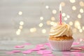 Delicious birthday cupcake with burning candle on grey table  against blurred lights Royalty Free Stock Photo