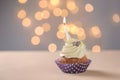Delicious birthday cupcake with burning candle on table against blurred lights Royalty Free Stock Photo