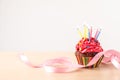 Delicious birthday cupcake with burning candles and ribbon on light wooden table Royalty Free Stock Photo