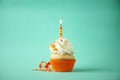 Delicious birthday cupcake with candle on light green background