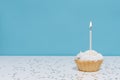 Delicious birthday Cupcake With One Candle on the white table with confetti stars on blue isolated background. place for your Royalty Free Stock Photo