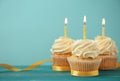 Delicious birthday cupcakes with burning candles on color wooden table Royalty Free Stock Photo