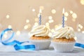 Delicious birthday cupcakes with burning candles on light table  against blurred lights Royalty Free Stock Photo