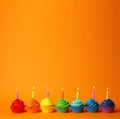 Delicious birthday cupcakes with candles on orange background