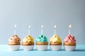 Delicious birthday cupcakes with candles on light background