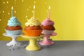 Delicious birthday cupcakes with candles on white table against blurred festive lights Royalty Free Stock Photo