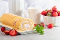 Delicious biscuit roll cake with fresh strawberries on a white stone table Royalty Free Stock Photo