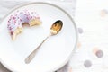 Delicious bite of donut with sprinkles on stylish plate with spoon on white table with confetti. Party concept. No diet. Candy bar