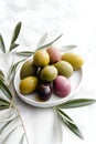 Delicious black, green and red olives with leaves in a bowl on white background. AI generated Royalty Free Stock Photo