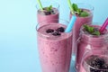 Delicious blackberry smoothie in different glassware on blue background