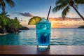 A delicious Blue Hawaii cocktail drink with a lemon slice and straw on a wooden table overlooking a tropical island at sunset.