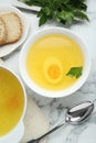 Delicious bouillon served on white marble table, flat lay