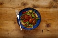 A delicious bowl of chipolte meat balls, couscous and vegetables, in a blue bowl on a rustic wooden background with a fork Royalty Free Stock Photo