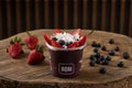 Delicious Brazilian AÃÂ§aÃÂ­ Cream, in a plastic Cup With Strawberry, coconut and blueberry Topping, in a rustic wooden background.