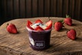 Delicious Brazilian AÃÂ§aÃÂ­ Cream, in a plastic Cup With Strawberry Topping, in a rustic wooden background. Summer acai smoothie