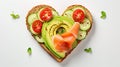 Delicious bread toasts in the shape of heart, with fresh avocado and red salted fish, on a white background