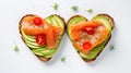 Delicious bread toasts in the shape of heart, with fresh avocado and red salted fish, on a white background