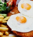 Delicious breaded beef dish with ham, cheese, fried eggs, accompanied by French fries. typical Argentine dish Royalty Free Stock Photo