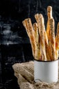 Delicious breadsticks grissini. Italian appetizers. Wooden dark background and burlap in metal oldstyle cup.