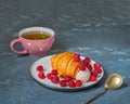 Delicious breakfast with berries and croissant. Raspberry and croissant on a light plate and may with mint in a pink mug