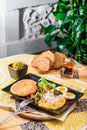 Breakfast with boiled eggs, pumpkin puree, lettuce, cheese and fresh bread on a black plate Royalty Free Stock Photo