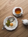 Delicious breakfast, brunch - fried egg, bread with butter, canned green peas and a cup of tea on a wooden background, top view Royalty Free Stock Photo