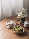 Delicious breakfast - cappuccino and avocado, eggs, microgreens toast on a round wooden table, top view. Aesthetic food concept