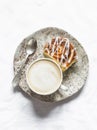 Delicious breakfast - cappuccino and cinnamon bun on a light background, top view