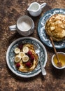 Delicious breakfast - cappuccino and pancakes with banana, raspberries, honey on a wooden background, top view